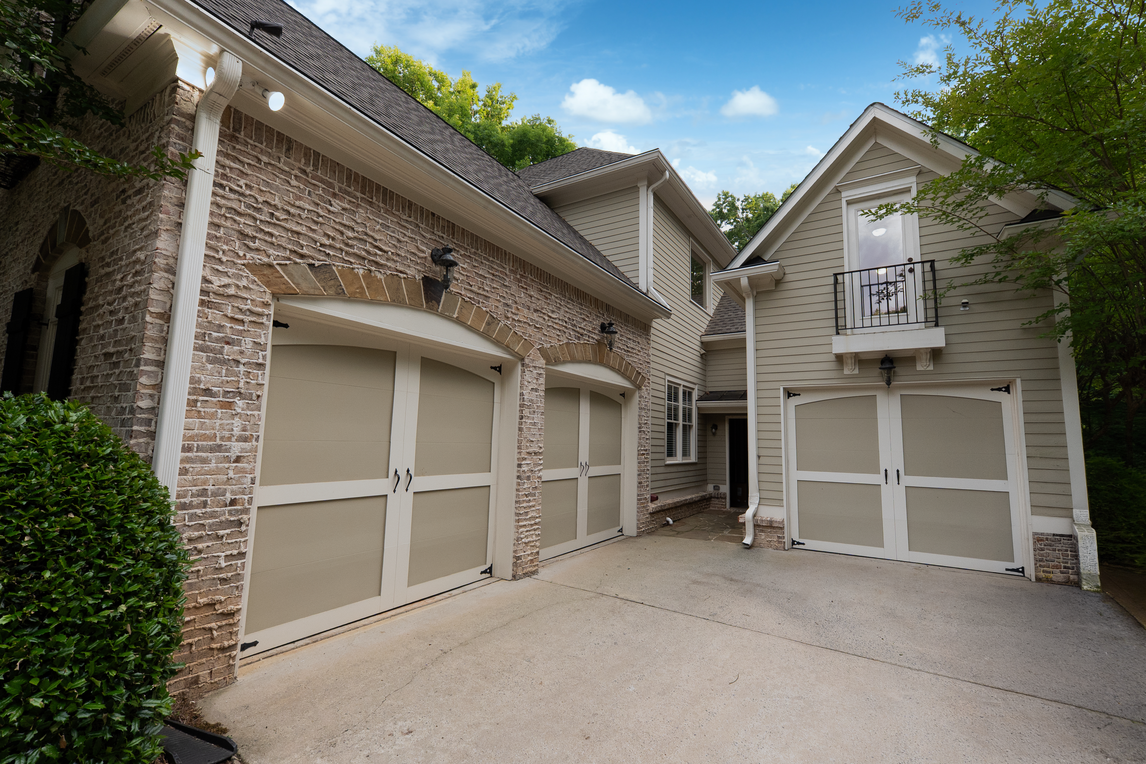 Three-car garage wing — arched brick surrounds, Juliette balcony and clean driveway court