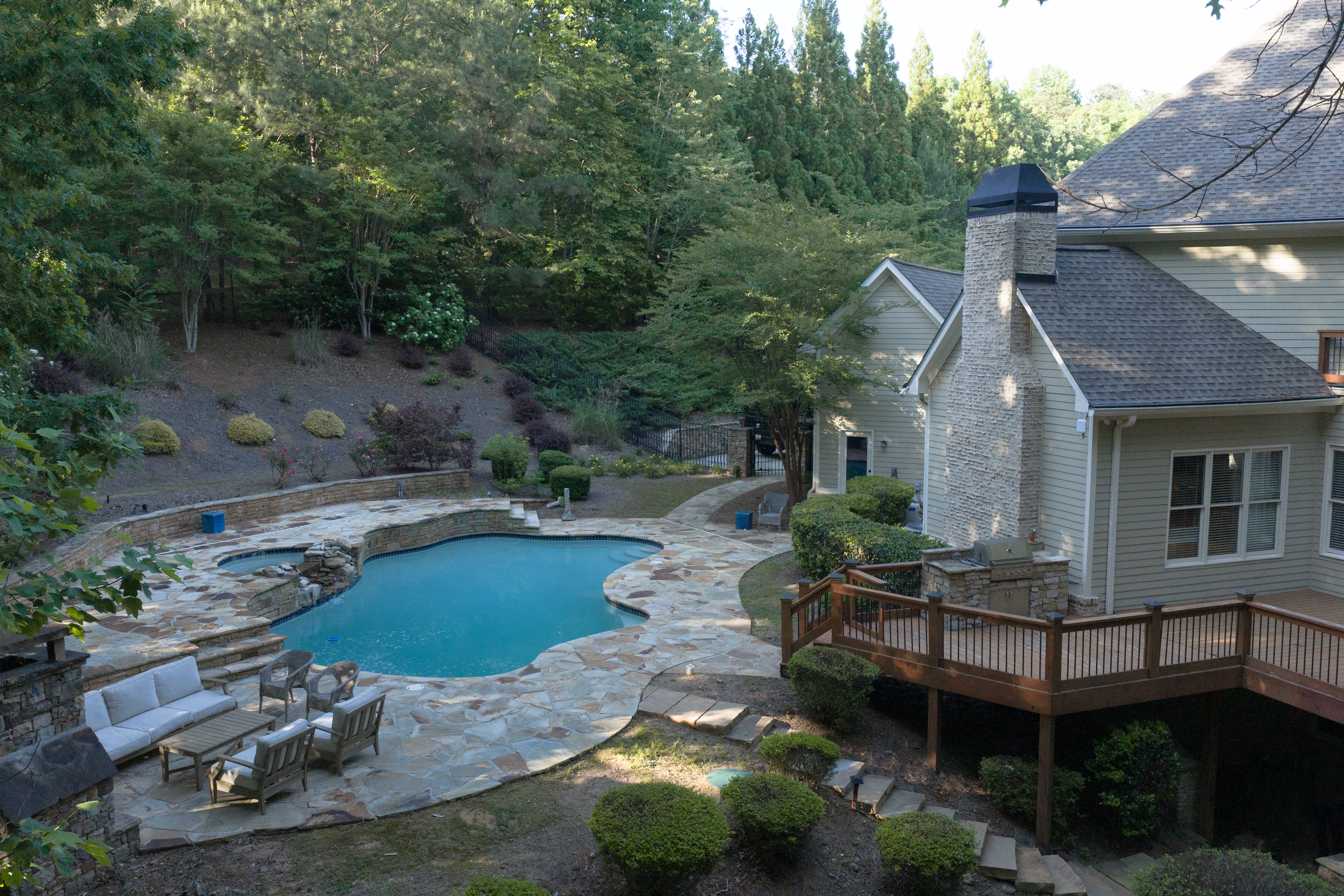 Back of house — stone chimney, cedar deck, pool and wooded hillside