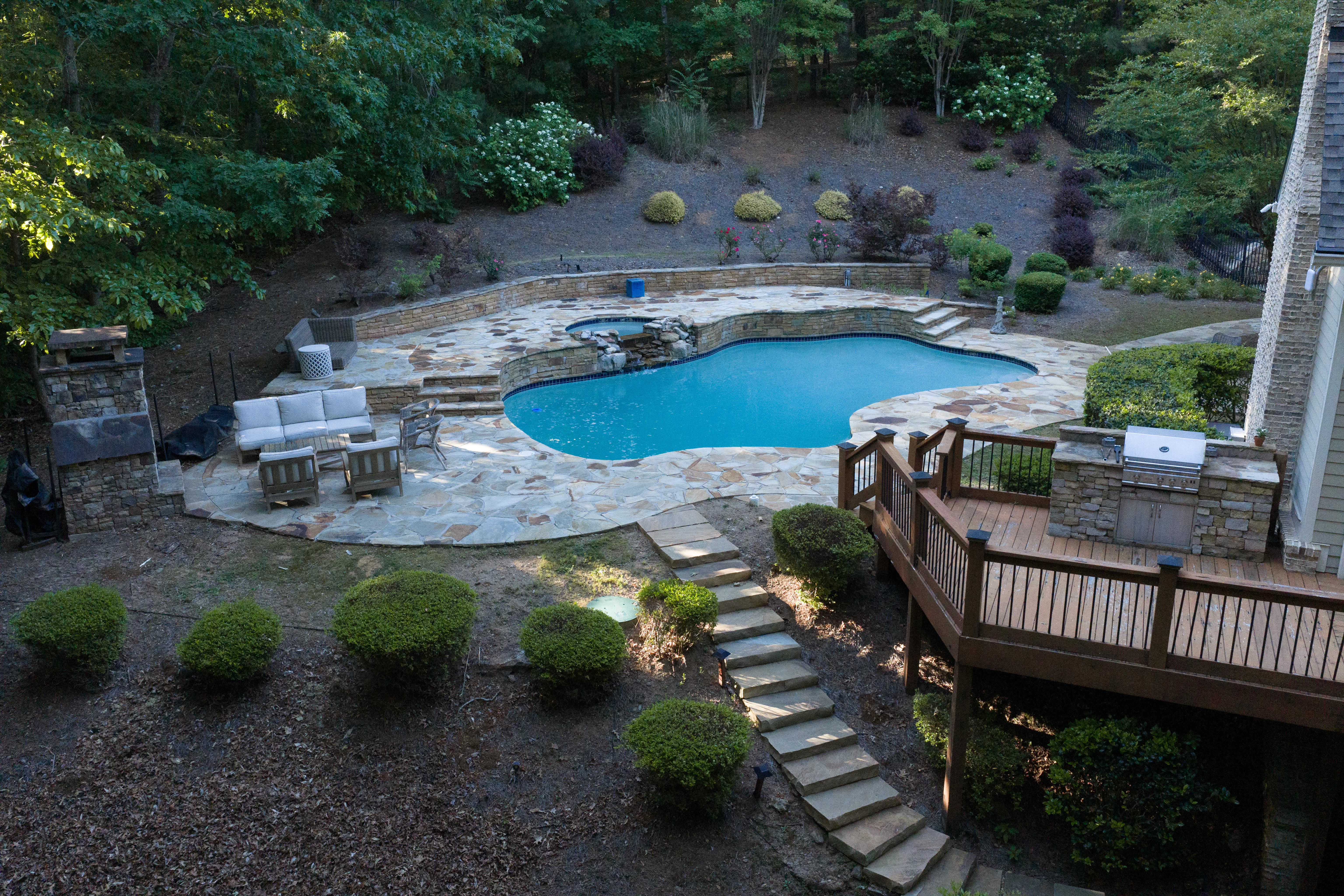 Stone steps lit by landscape lighting descending to the pool at dusk