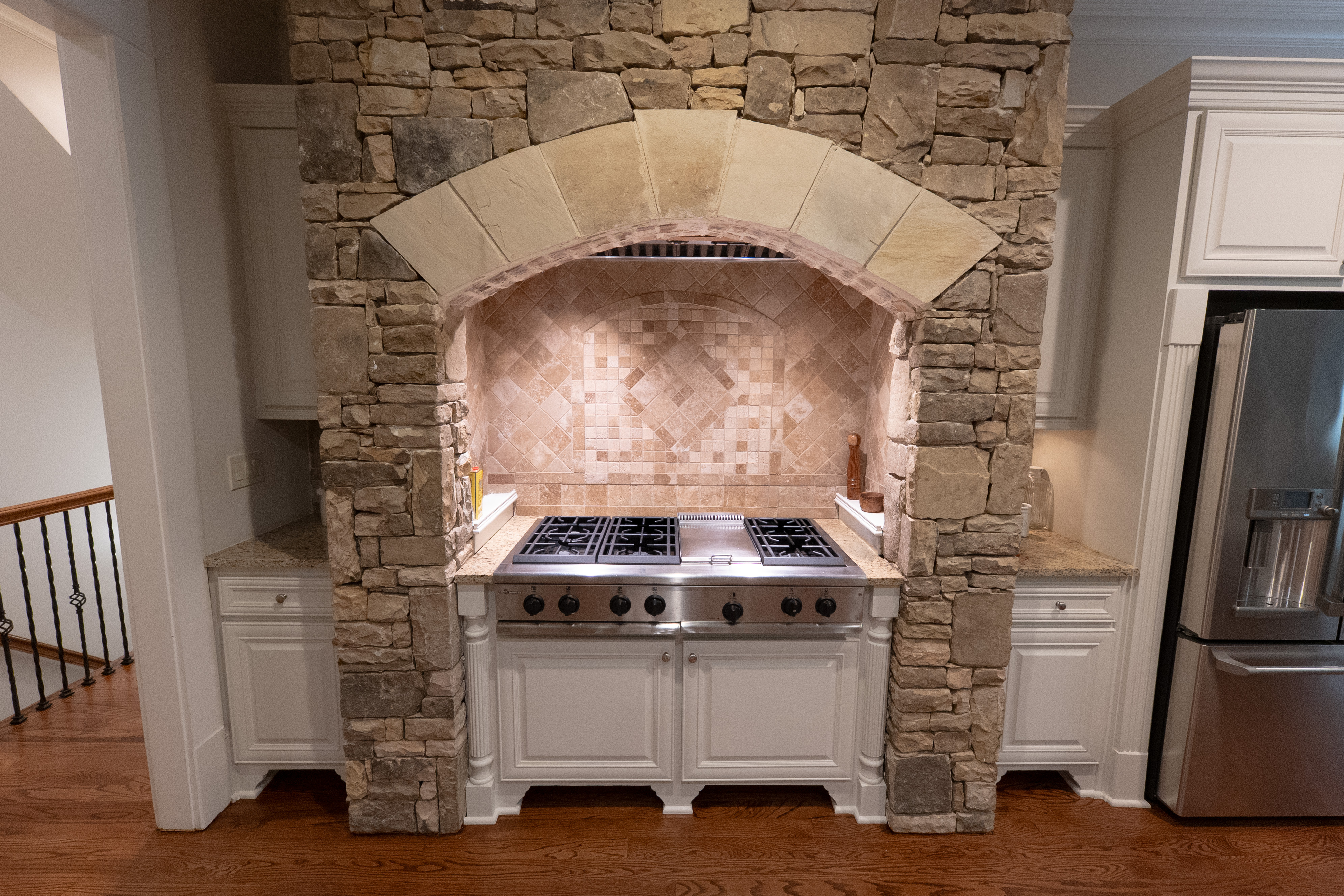Stone arch range hood — keystone detail and diamond backsplash
